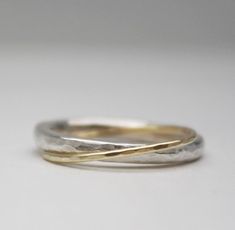 two gold and silver rings sitting on top of a white surface with one ring in the middle