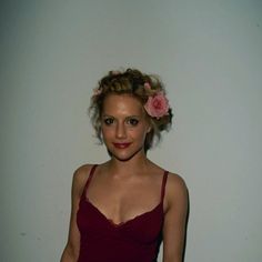 a woman in a red dress posing for the camera with a flower in her hair