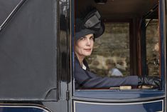 a woman wearing a hat sitting in the driver's seat of a blue train