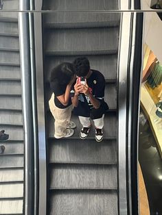 a young boy sitting on an escalator looking at his cell phone while he takes a photo