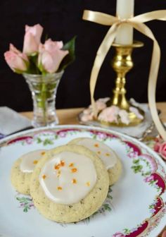 two cookies with icing on a plate next to a candle and flowers in a vase