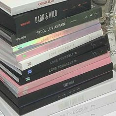 a stack of books sitting on top of a white desk next to a computer keyboard