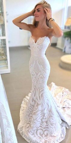 a woman in a white wedding dress standing next to a mirror with her hand on her head