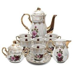 a white tea set with pink flowers on the side and gold trimmings around it