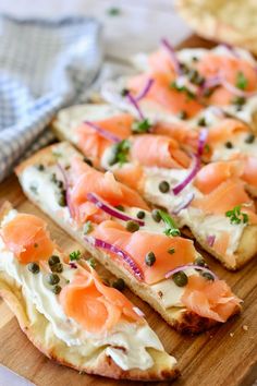 slices of bread with smoked salmon and capers on them sitting on a cutting board