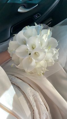 a bouquet of white flowers sitting in the front seat of a car on a wedding day