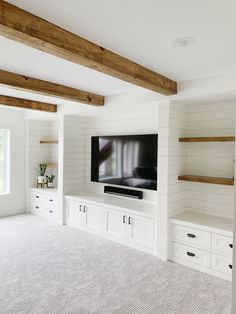 a living room with white walls and built - in shelving units, including a flat screen tv