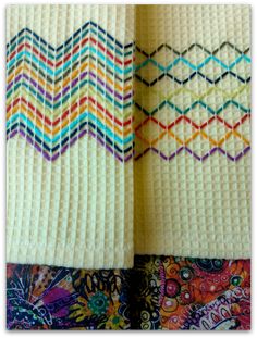 two white towels with multicolored chevrons on top of each other in front of a colorful background