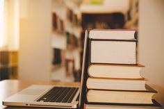 a stack of books sitting on top of a laptop computer next to a pile of books