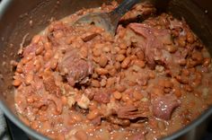 a pot filled with beans and meat on top of a stove