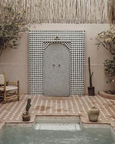 an outdoor area with potted plants and a tiled wall in the background, along with two wooden chairs