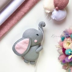 an elephant keychain hanging from a string next to other stuffed animals and flowers