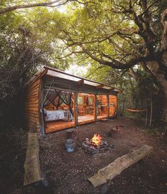 a small cabin in the woods with a fire pit