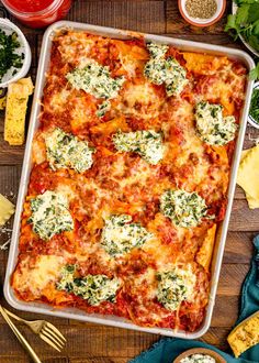 a casserole dish with spinach and cheese on it, surrounded by other dishes