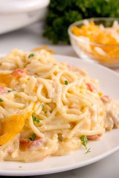 a white plate topped with pasta covered in cheese and sauce next to other food items