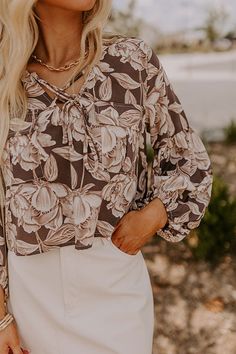 - This trendy top is the must-have floral for the season! With its beautiful print, puffy sleeves, and cropped cut, it's perfect for a chic vibe with a touch of feminine charm. - Unlined semi-sheer material with a brown and cream floral print -A v-cut neckline with a tie detail - ¾ puffy sleeves with elastic cuffs - Functional chest pockets - A relaxed silhouette that ends in a subtly cropped hemline Chic Cropped Floral Print Crop Top, Floral Print Crop Top For Brunch, Chic Floral Print Crop Top For Brunch, Floral Print Crop Top For Spring Brunch, Chic Floral Print Crop Top For Fall, Chic Long Sleeve Floral Print Crop Top, Chic Floral Print Crop Top For Spring, Flowy Chic Crop Top For Spring, Chic Flowy Crop Top For Spring