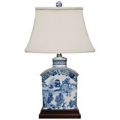 a blue and white vase lamp with a shade on the top is sitting on a table