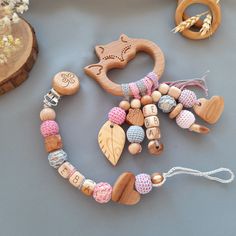 wooden toys and beads are arranged on a gray surface, including a pacifier toy