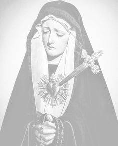 a black and white photo of a nun holding a cross in her hands with both hands