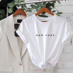 two white shirts hanging up against a brick wall with the words new york printed on them