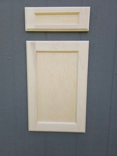 two unfinished wooden frames hang on the side of a gray painted wall with wood trim