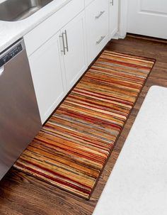 a kitchen area with a sink, dishwasher and rug