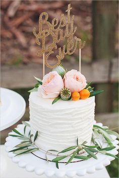 a white cake topped with flowers and a wooden sign