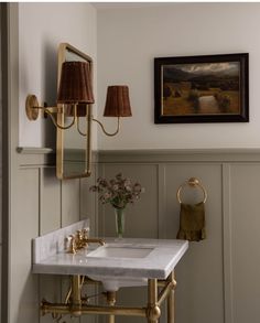 a bathroom sink sitting under a mirror next to a painting