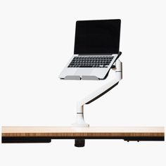 a laptop is sitting on top of a desk with a white arm and black keyboard