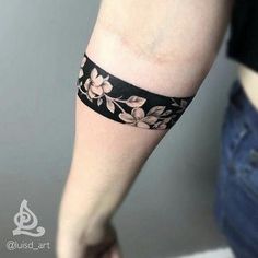 a woman's arm with a black and white flower tattoo on the left forearm