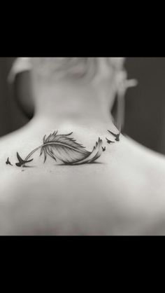 a woman's back neck with a feather tattoo on the left side of her neck