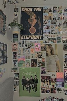 a wall covered in posters and pictures next to a bed