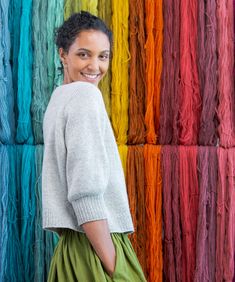 a woman standing in front of a rainbow colored wall