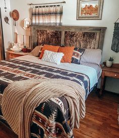 a bedroom with a bed, nightstands and pictures on the wall above it is decorated in native american style