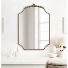 a mirror sitting on top of a white table next to a vase and potted plant