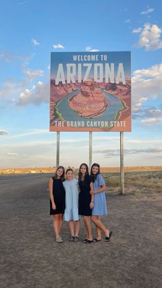 three women standing in front of the welcome sign to arizona, which is located at the grand canyon state park