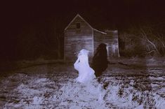 two people standing in front of a barn at night with one person wearing a ghost costume