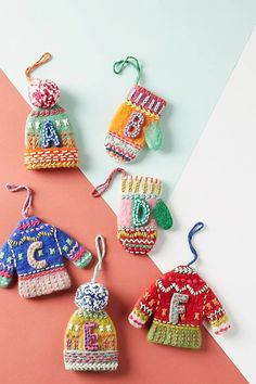 knitted christmas ornaments are displayed on a pink and white background, including one with an ornament in the shape of a sweater