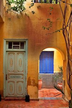 an old building with a blue door and some plants in front of the entrance to it