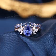 a tan and blue ring sitting on top of a blue satin material with gold accents