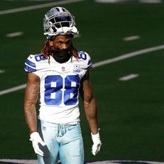 a football player wearing a helmet and gloves on the field with his hands in his pockets