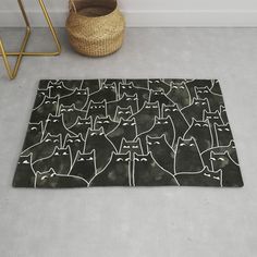 a black rug with white cats on it next to a basket and planter in the corner