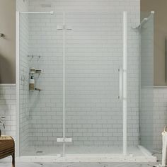 a walk in shower sitting next to a white tiled wall and wooden chair on the floor