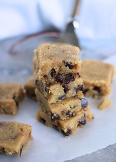 several pieces of chocolate chip cookie bars stacked on top of each other with a spoon in the background