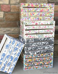 several boxes are stacked on top of each other in front of a brick wall with flowers painted on them