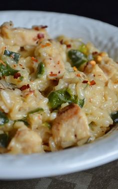 a white plate topped with pasta and meat covered in cheese, green peppers and seasoning