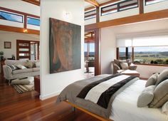 a large bedroom with wood floors and white walls, along with an art piece on the wall