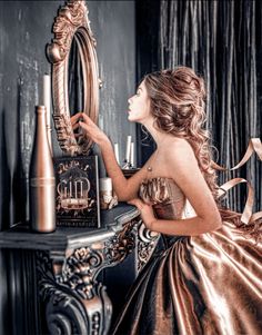 a woman in a gold dress is looking into a mirror