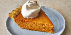 a piece of pumpkin pie with whipped cream on top sits on a blue and white plate