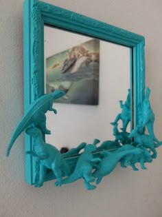 a mirror that has some blue plastic animals in front of it and a painting on the wall behind it